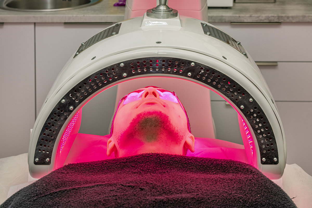 Paciente recibiendo tratamiento facial con luz LED en clínica estética.