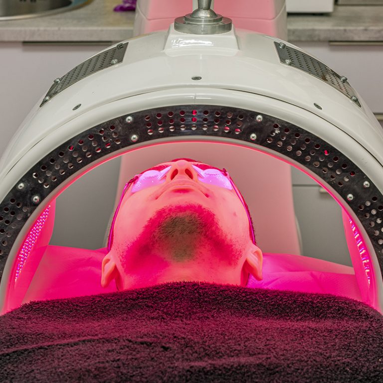 Paciente recibiendo tratamiento facial con luz LED en clínica estética.